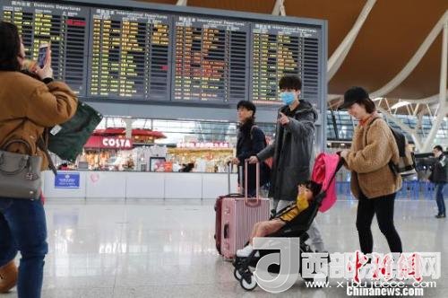 旅客帶著孩子前往辦票柜臺辦理登機手續(xù)?！∫罅⑶?攝