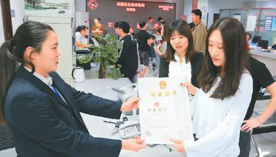 河北省承德市網(wǎng)絡(luò)代購經(jīng)營者陳晨(右)從工作人員手中接過帶有統(tǒng)一社會信用代碼的營業(yè)執(zhí)照。 劉環(huán)宇攝(人民圖片)