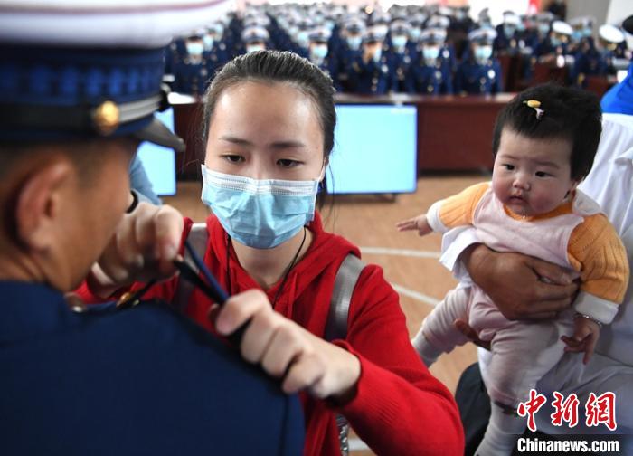 新消防員楊振的妻子彭莉與女兒現(xiàn)場見證丈夫加入“火焰藍(lán)”的神圣時刻?！⒅铱?攝