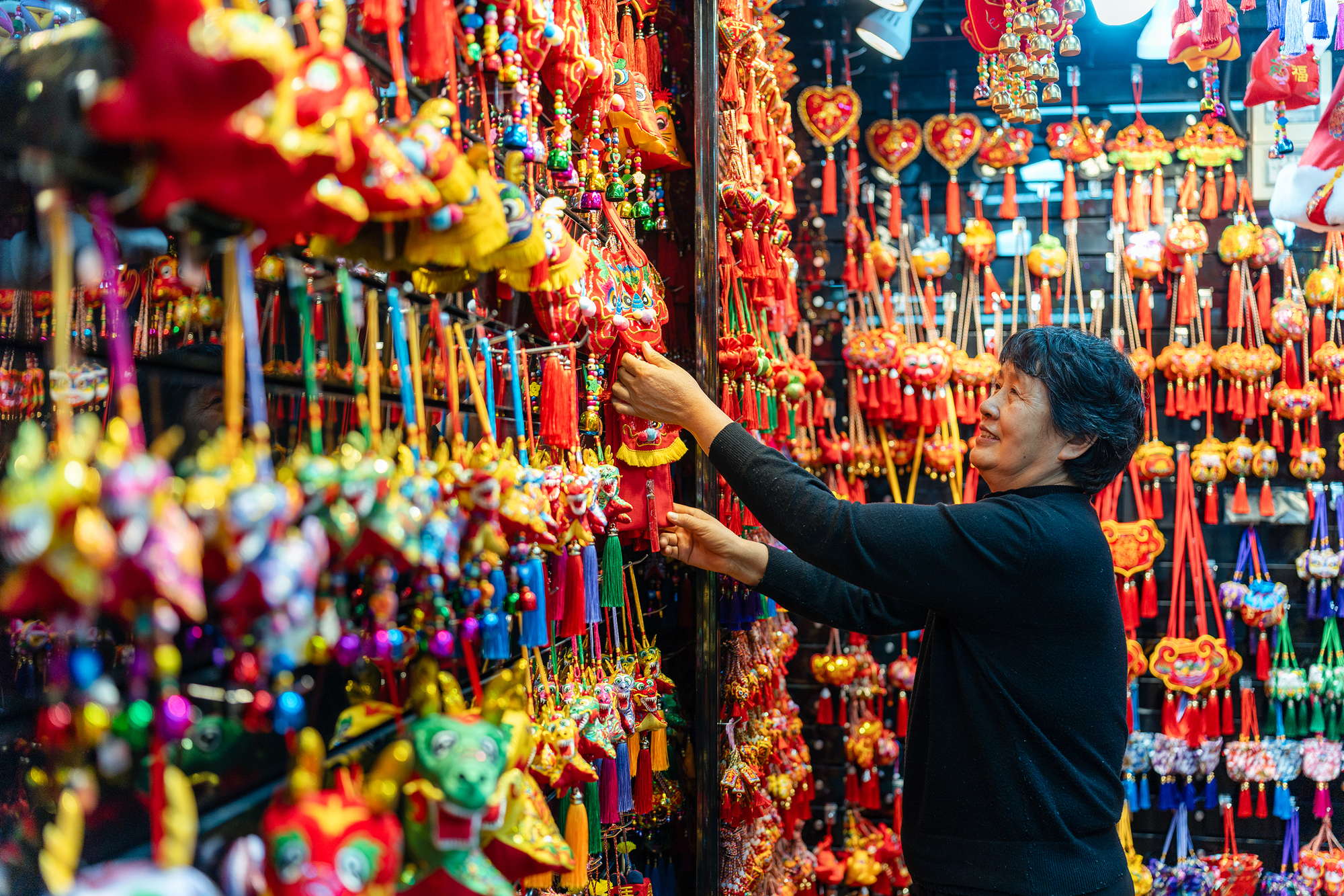 2023年12月11日，金華義烏國際商貿(mào)城，龍年喜慶用品掛滿攤位，顧客正在挑選中。