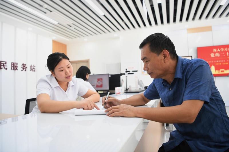 2023年5月23日，河北雄安新區(qū)容東片區(qū)南文營社區(qū)居民（右）在社區(qū)便民服務站辦理業(yè)務。
